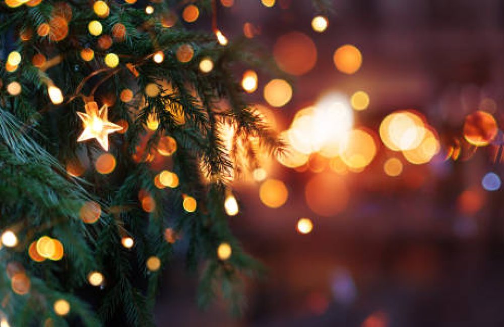 Christmas tree with garland lights. Evening city with blurred background and bright lights